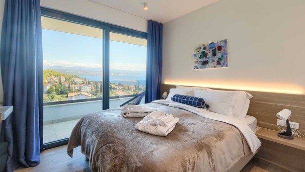 Una habitación de hotel moderna con una cama grande, vistas a un paisaje urbano y un cuadro en la pared.