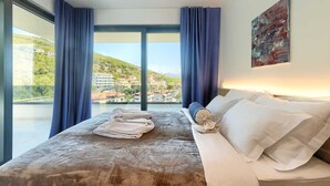 Habitación de hotel con una cama grande, vistas a la ciudad y un cuadro en la pared.