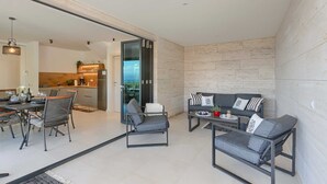 Un espacio habitable moderno con comedor, un conjunto de sofás y una cocina visible a través de una puerta abierta.