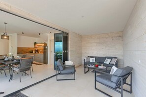 Um espaço moderno com área de refeições, sofás e cozinha visível através de uma porta aberta.