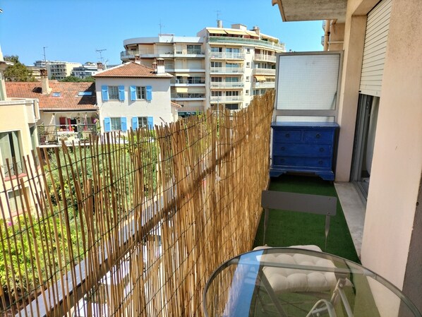 Un balcon donnant sur un quartier résidentiel, avec vue sur un immeuble à plusieurs étages et un meuble bleu.