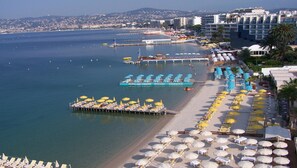 A coastal resort with a beach, a boat dock, and a row of sunbeds and umbrellas.