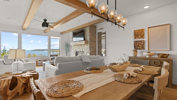 Ein modernes Wohnzimmer mit einem großen Holzesstisch, einem Kamin und Meerblick.