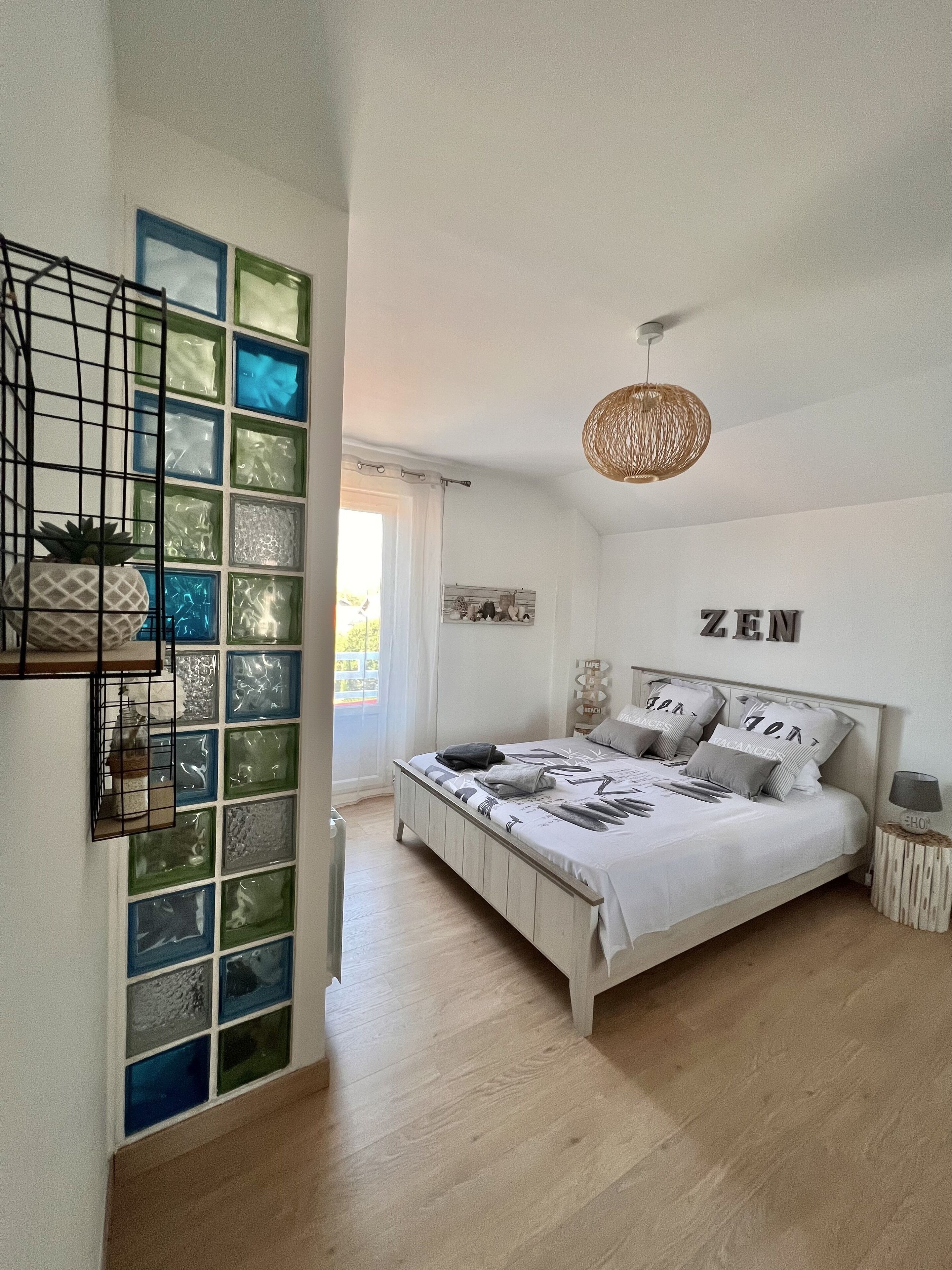 Ein Schlafzimmer mit Bett, einer Pendelleuchte und einer Wand mit dem Schriftzug 'ZEN'.