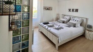 Ein Schlafzimmer mit Bett, einer Pendelleuchte und einer Wand mit dem Schriftzug 'ZEN'.