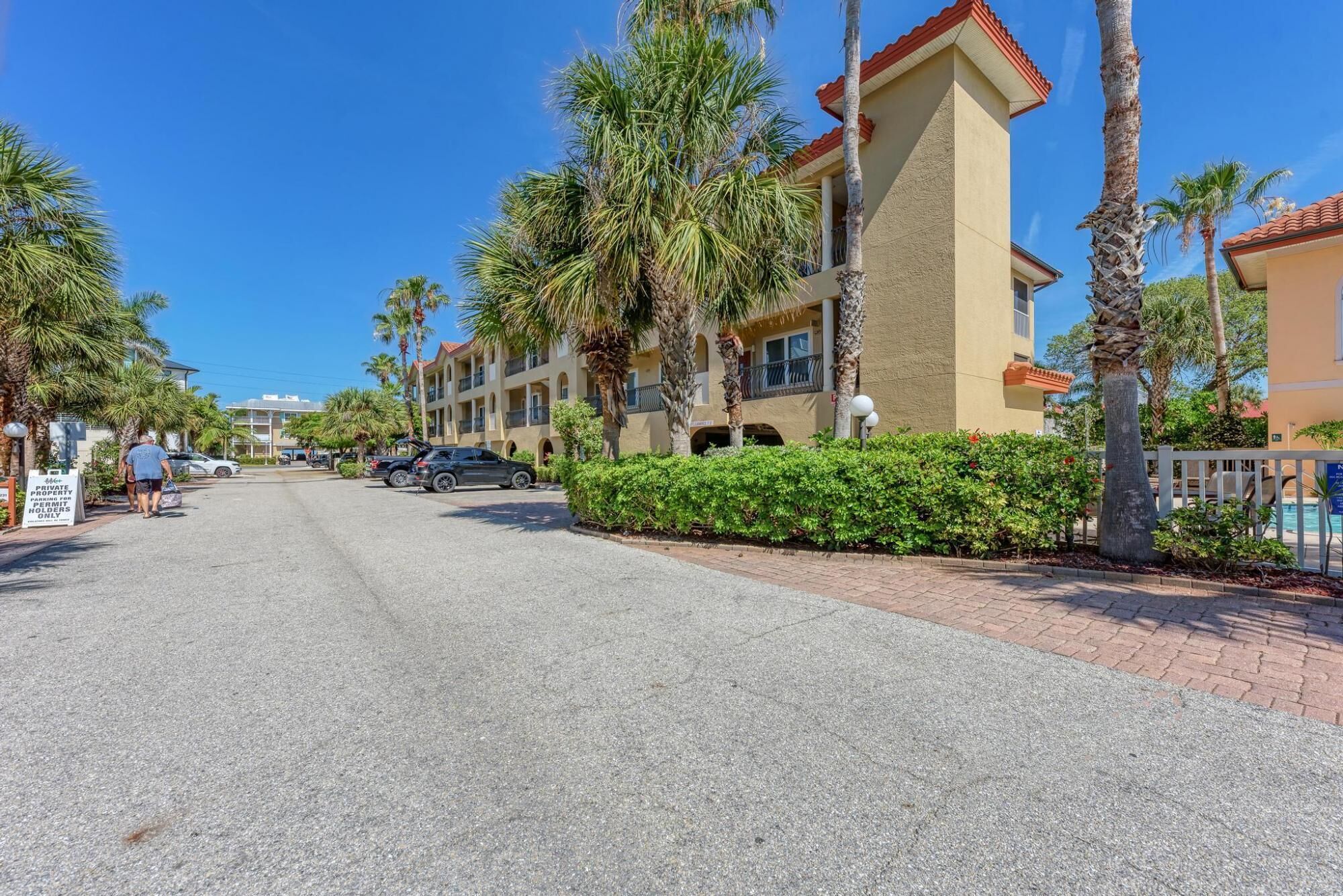 A street view of a hotel with a row of buildings, palm trees, and a clear blue sky.