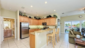 A spacious kitchen with wooden cabinets, a stainless steel refrigerator, and a granite countertop. - Bradenton Beach Club Bliss-2 Bedroom-2 Bathroom Condo-2 Pools-hottub-private Beach Access (Bradenton Beach)