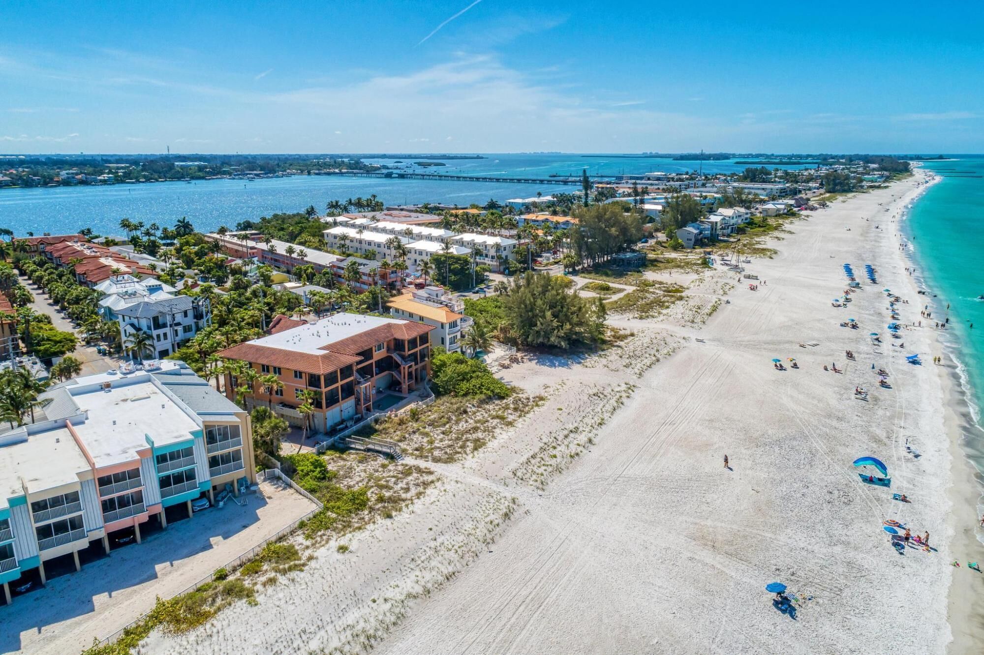 A coastal area with a sandy beach, beachfront properties, and a marina.