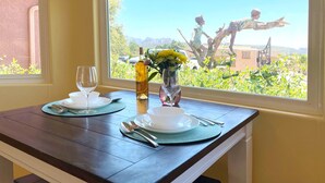 Mesa lista con platos, cubiertos y una botella de vino, con vistas a un jardín y una estatua en el exterior.