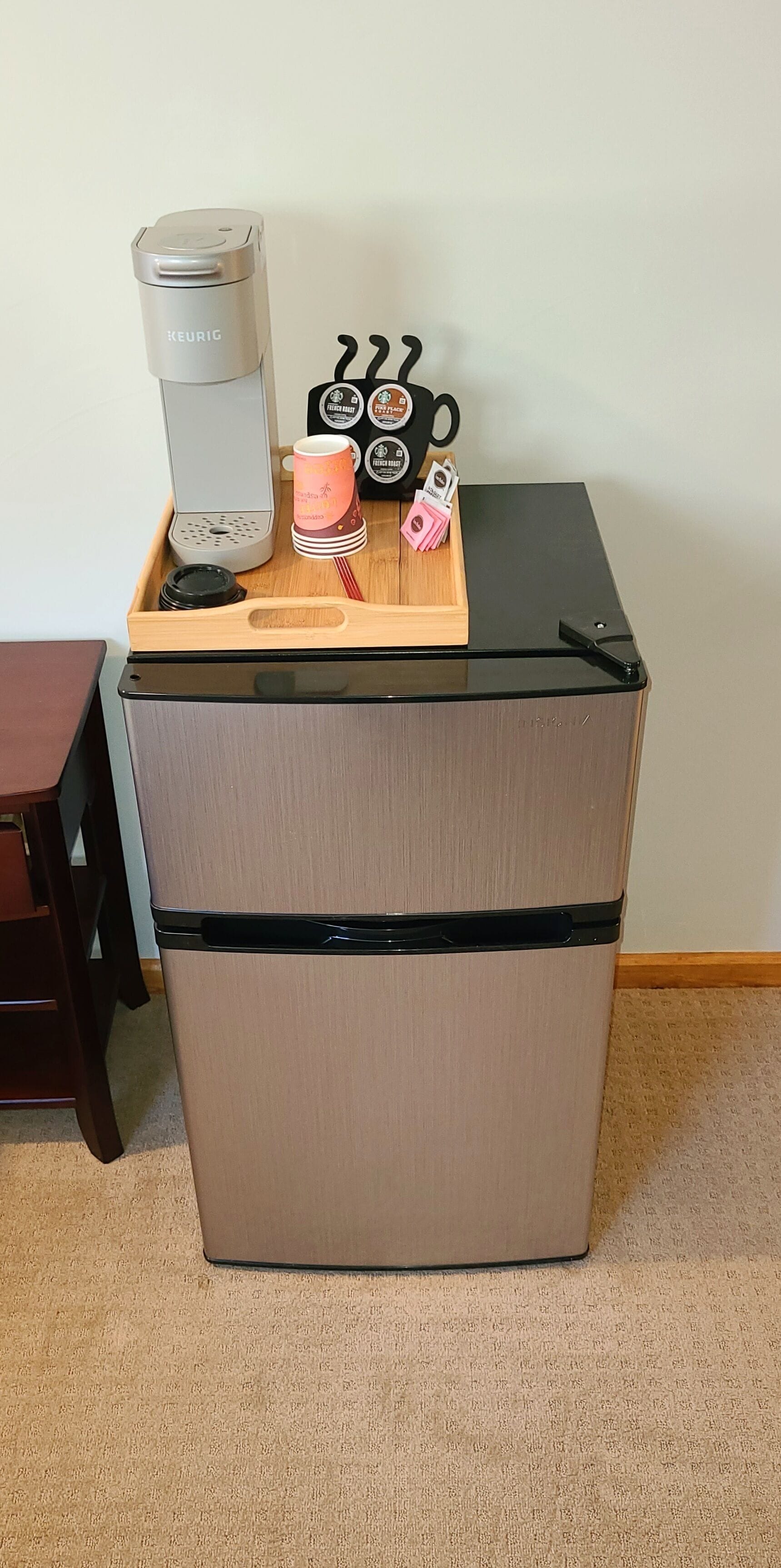 A compact kitchenette with a coffee maker, a mug, and a knife block on top.