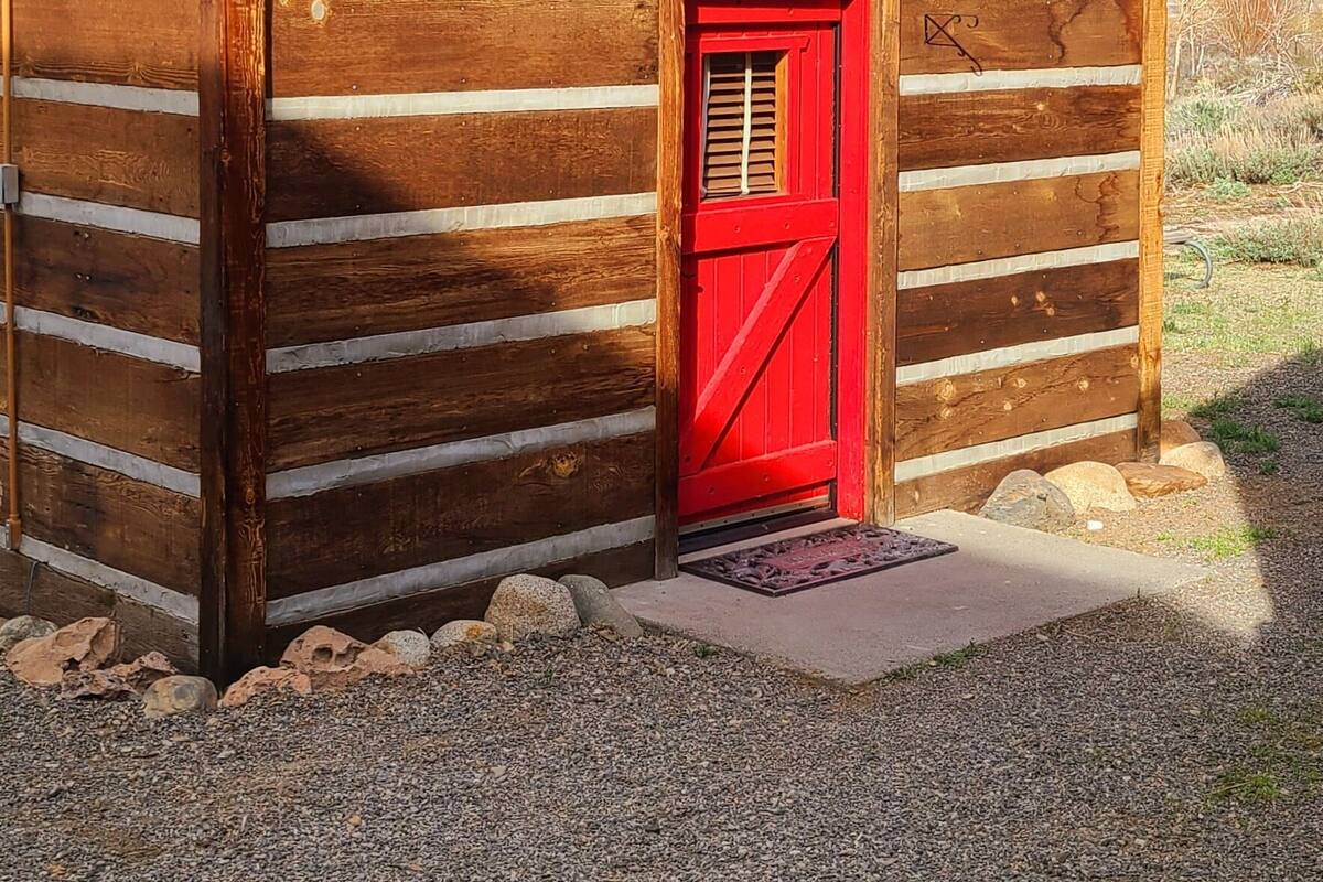 Uma cabana de toras com porta vermelha e uma placa que diz 'Ice House'.
