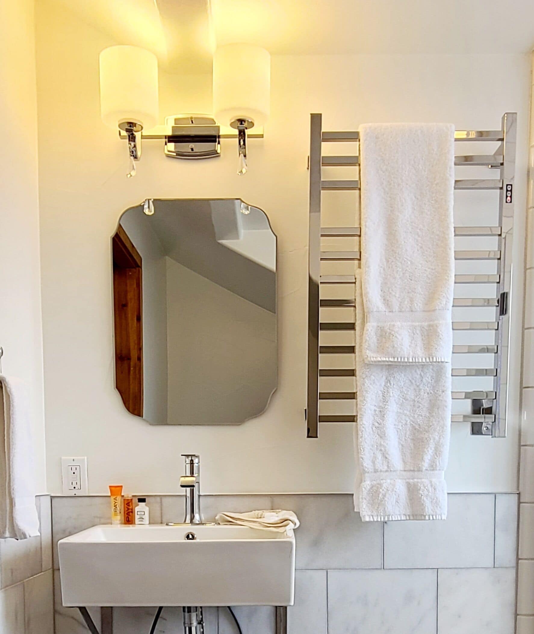 Een badkamer met een grote spiegel, een wastafel en een handdoekhouder.