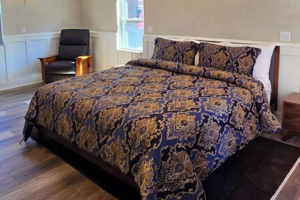Um quarto espaçoso com uma cama grande, um candelabro e luminárias na parede.