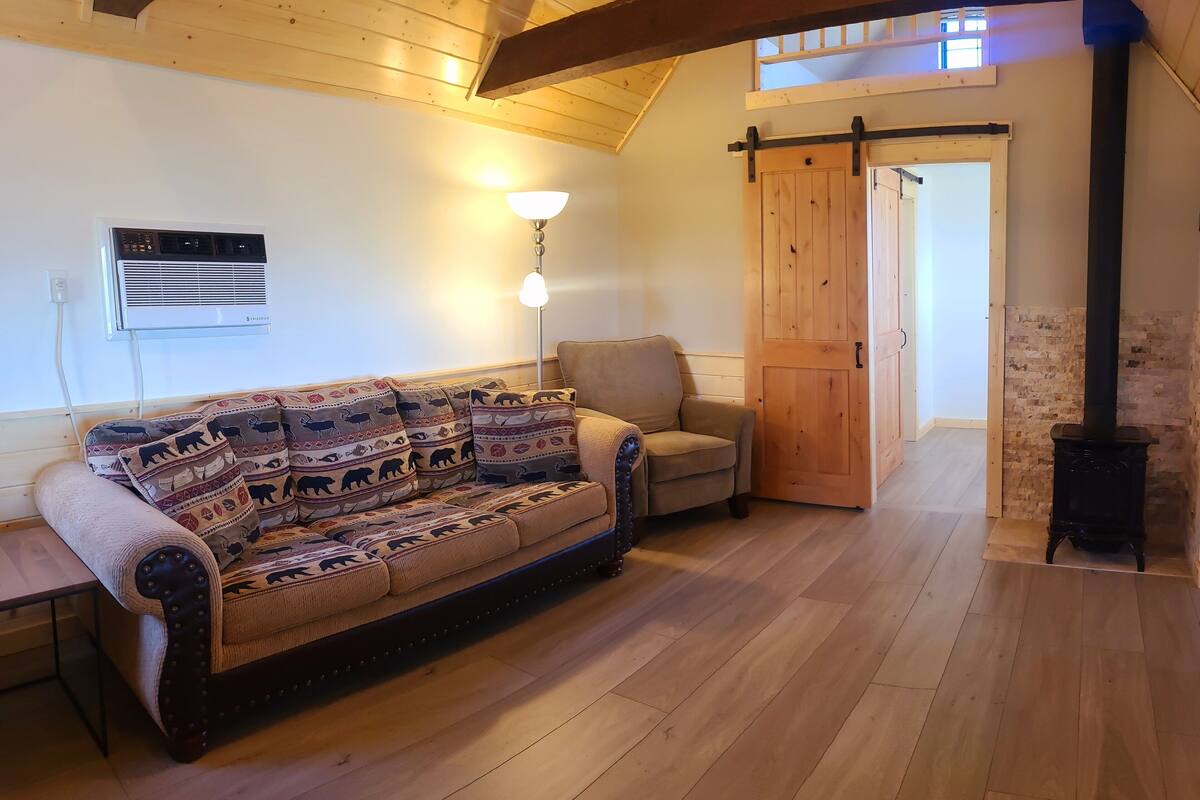 Uma sala de estar acolhedora com um sofá, um candeeiro, uma porta de madeira e uma lareira.