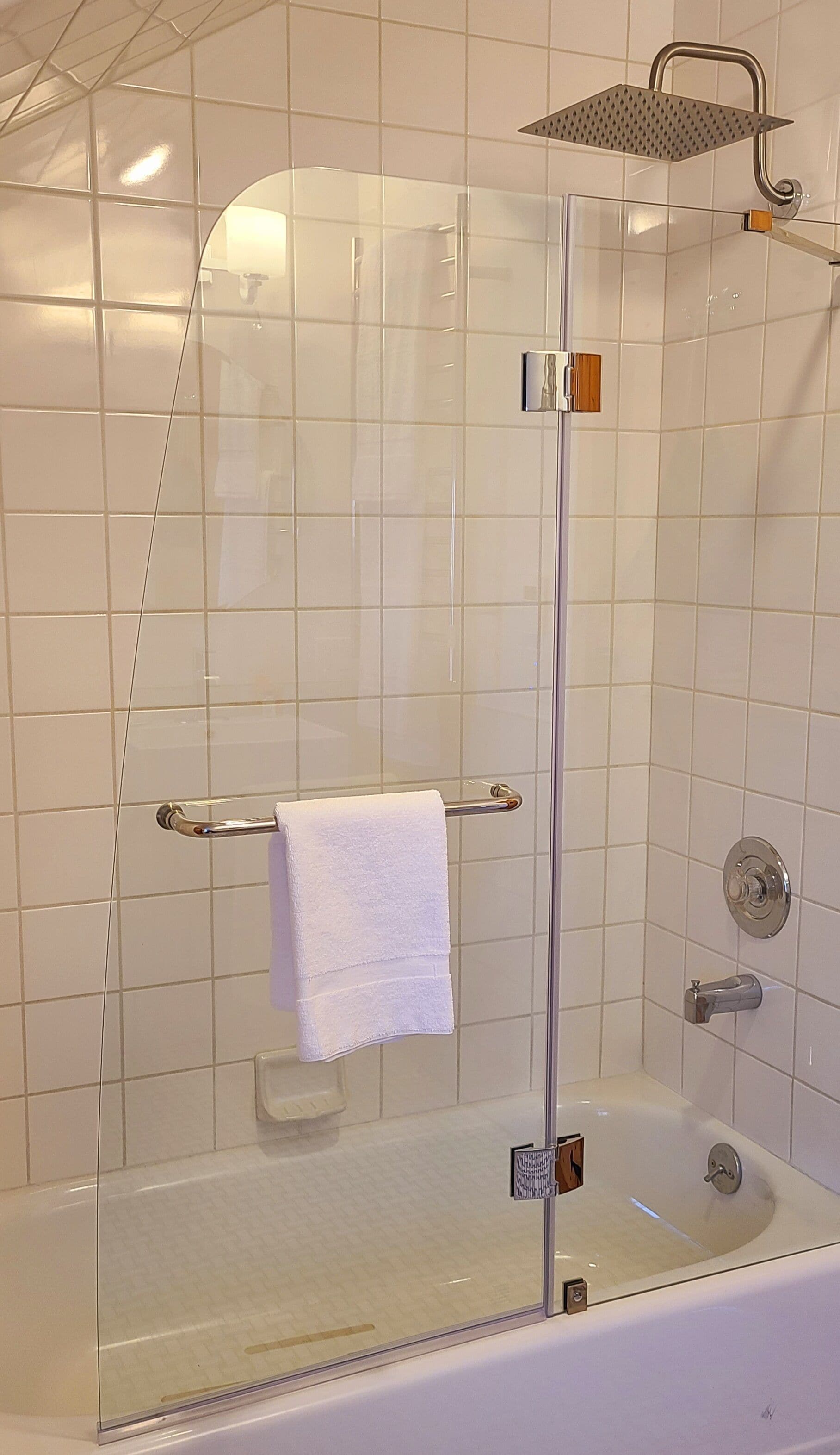 Cabina doccia in vetro con soffione a mano, portasciuga e vasca da bagno con pareti in vetro.
