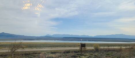 A remote landscape with mountains, a body of water, and a small structure in the foreground.