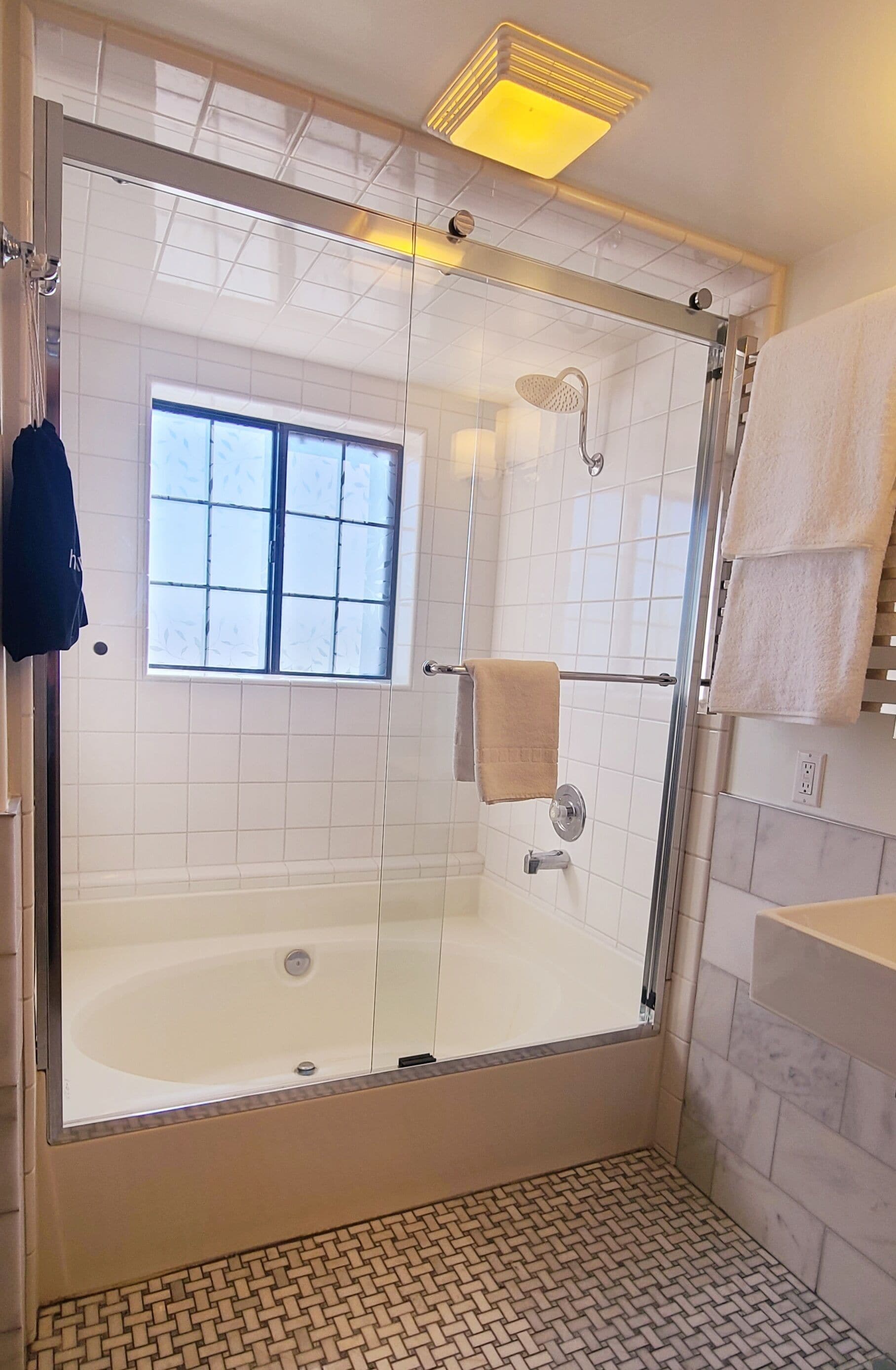 Une douche à l’italienne avec parois en verre, une baignoire, une fenêtre et un porte-serviettes.