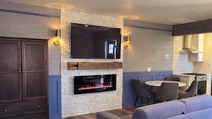 A modern living room with a fireplace, a flat-screen TV, and a sofa.