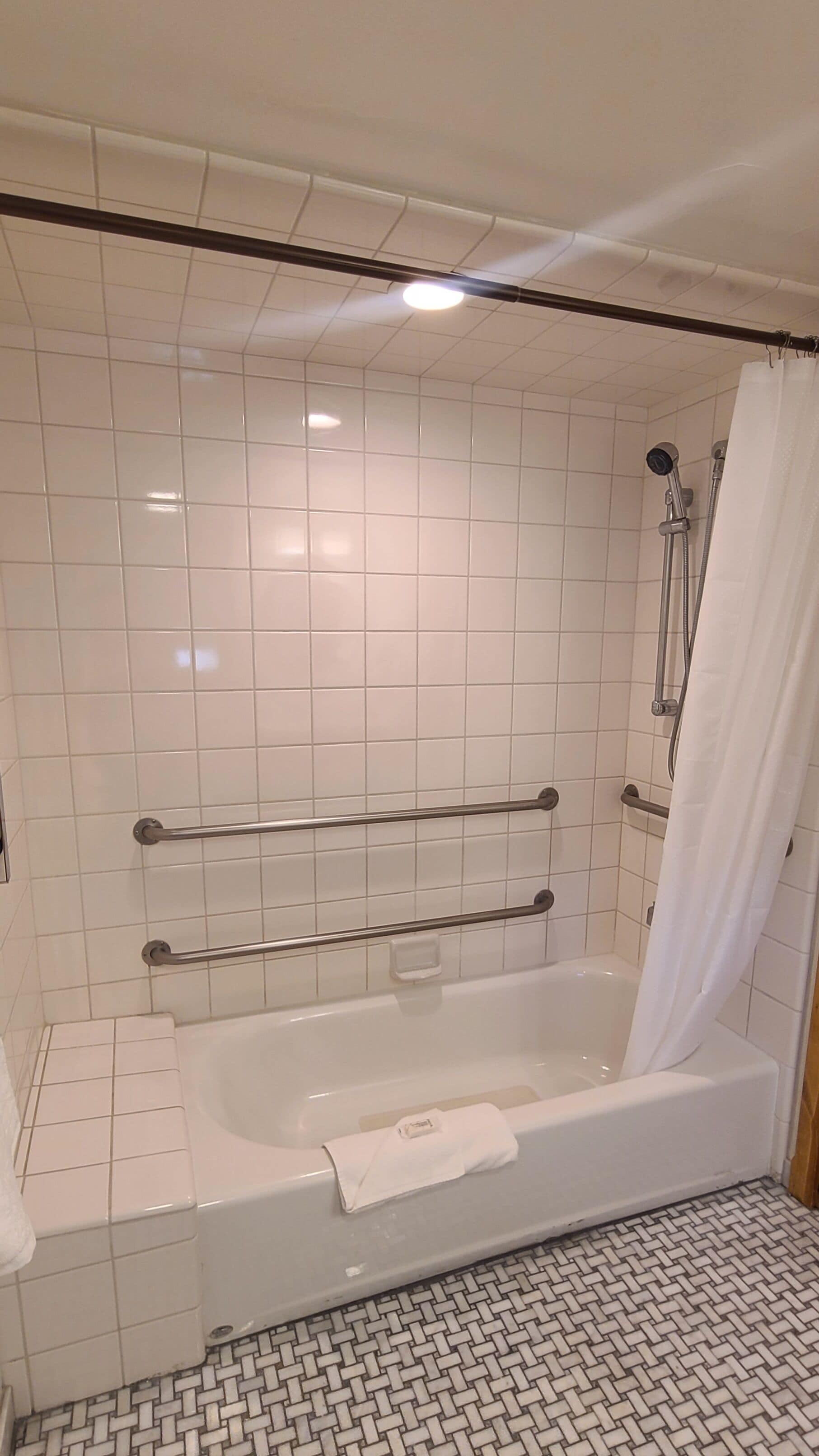 Et moderne badeværelse med badekar, bruser og gelænder.