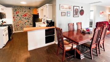 Enjoy meals in the kitchen with a central island and dining table, surrounded by framed pictures and a decorative wall hanging.