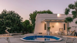 A modern house with a swimming pool, outdoor seating, and a garden.