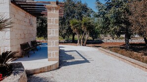 A courtyard with a stone bench, a pergola, and a gravel path.