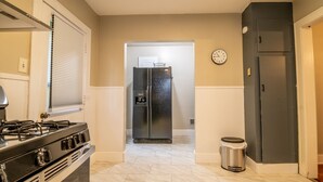 Una cocina con estufa, refrigerador y cubo de basura.