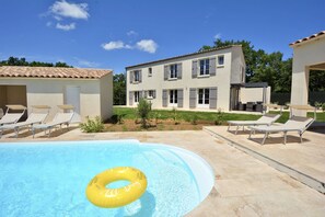 A swimming pool with lounge chairs and a yellow inflatable ring.