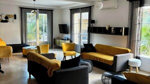 Un salon moderne avec un canapé, des fauteuils et un téléviseur.