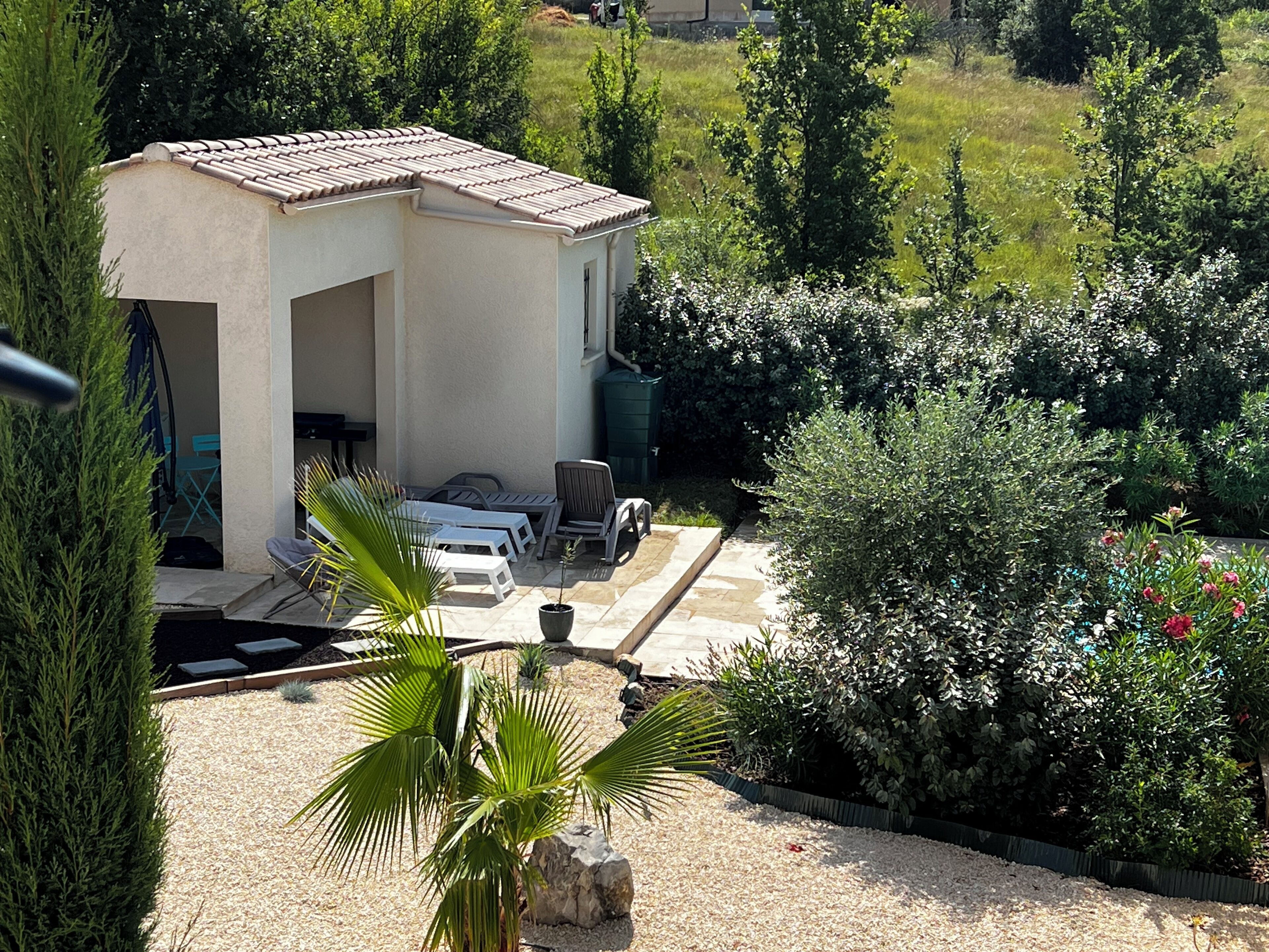A house with a patio area featuring outdoor furniture, surrounded by lush greenery and a well-maintained garden.