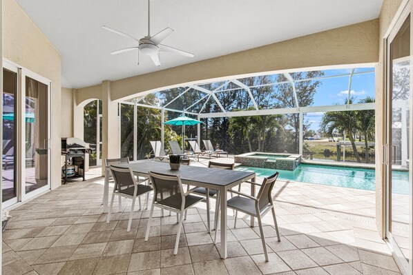 A covered outdoor area with a pool, a table with chairs, and a ceiling fan. - Luxury villa, large pool and jacuzzi (Cape Coral)