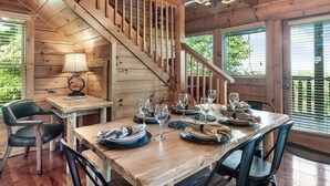 A wooden interior with a staircase, dining table set with plates and glasses, and a lamp. - E.Z drive! WOW VIEWS, hotTUB 🎱 POOL TABLE, fireplace Close to Gatbg & Dollywood (Sevierville)