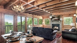 A wooden cabin interior with a dining table set for six, a fireplace, and a sofa. - E.Z drive! WOW VIEWS, hotTUB 🎱 POOL TABLE, fireplace Close to Gatbg & Dollywood (Sevierville)