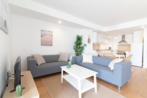 A modern living room with a grey sofa, a white coffee table, and a television.