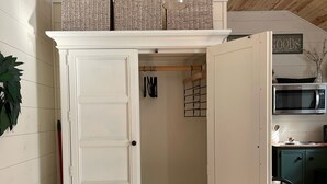 A white wardrobe with open doors, a hanging rod, and a light fixture above.