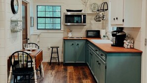 A kitchen with wooden ceiling, white walls, and green cabinets.