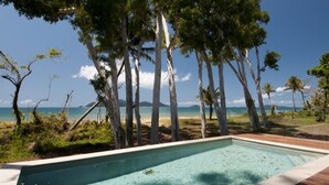 A swimming pool with a view of the ocean and trees.