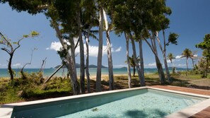 A swimming pool with a view of the ocean and trees.