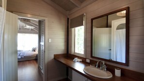 A bathroom with a wooden vanity, a large mirror, and a window.