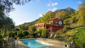 Eine Villa mit Swimmingpool, umgeben von üppiger Vegetation und einer gebirgigen Landschaft.