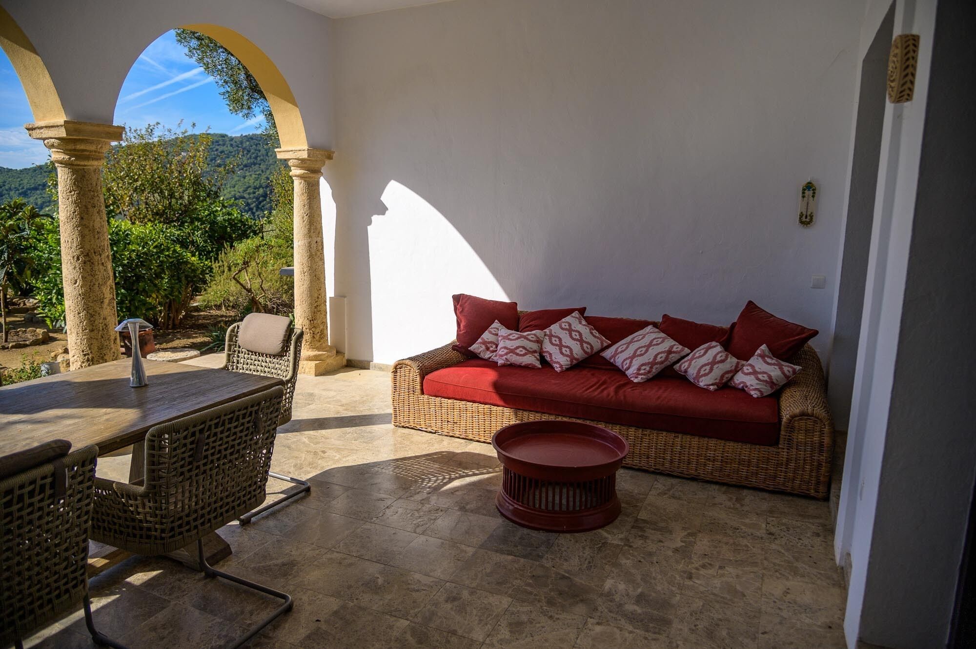 A cozy outdoor seating area with wicker furniture, a red sofa, and a small round table.