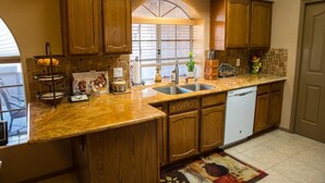 A kitchen with wooden cabinets, a double sink, and a dishwasher.