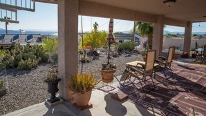 An outdoor patio area with seating, potted plants, and a view of a desert landscape.