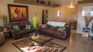 A living room with two brown leather sofas, a glass coffee table, and a patterned rug.