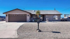 A single-story house with a garage, a covered patio, and a small garden area with a palm tree.