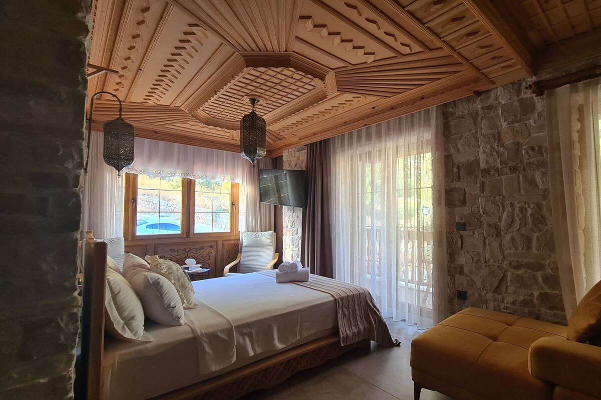 Un dormitorio con una cama grande, un sofá y una pared de piedra.