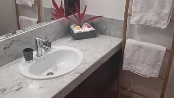 A bathroom with a marble sink, a mirror, and a towel rack with multiple towels.