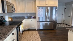 A kitchen with white cabinets, stainless steel appliances, and a patterned rug. - Cheerful, spacious, sunny & comfy 4-bdrm home (Rock Springs)