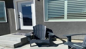 A patio with a single Adirondack chair, a small table, and a door with a window. - Cheerful, spacious, sunny & comfy 4-bdrm home (Rock Springs)