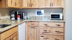 A kitchen with wooden cabinets, granite countertop, and a dishwasher. - Seven Springs Mtn. Villas Condo - Ski, Golf, Hike, Sporting Clays, & Relaxation! (Champion)